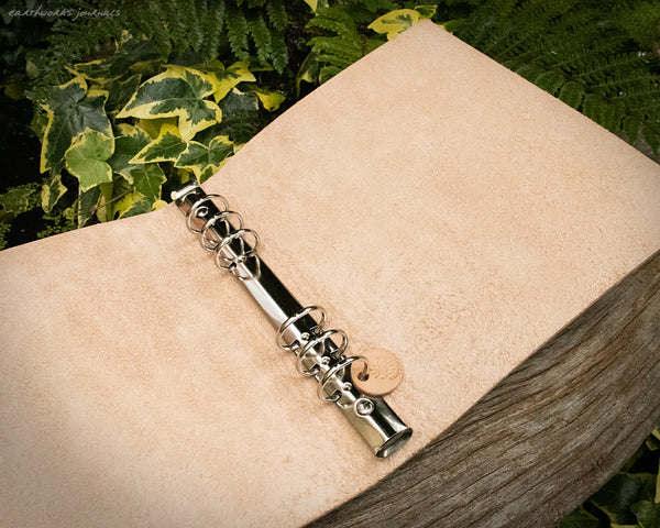 an a5 leather 6 ring binder open on a weathered piece of wood, made by earthworks journals
