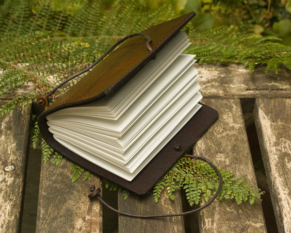 open small brown leather journal surrounded by fern leaves, made by earthworks journals